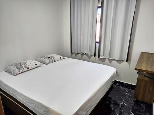 ein weißes Bett in einem Zimmer mit Fenster in der Unterkunft Edifício Louise – Apto 301 in Chapecó