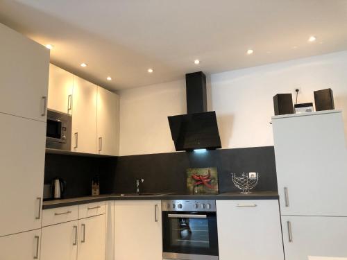 a kitchen with white cabinets and a stove top oven at Haus Frauken in Grömitz