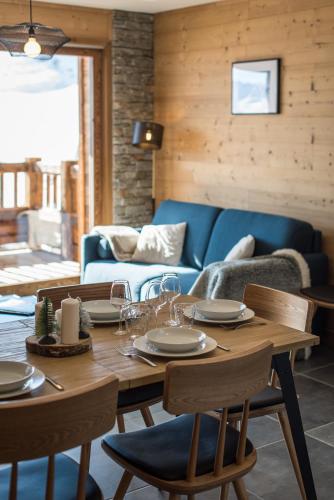 une salle à manger avec une table et un canapé bleu dans l'établissement Appartement moderne et chaleureux sur les pistes, à La Toussuire