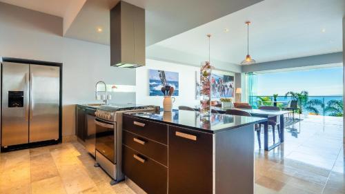a kitchen with a stainless steel refrigerator and a table at Paramount Bay - 308 Peaceful Luxury View 2 BR in Puerto Vallarta