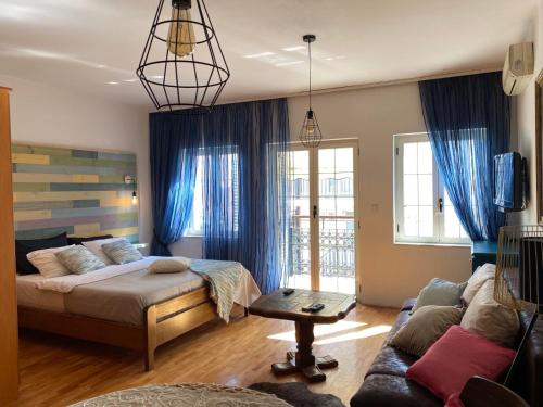 1 dormitorio con cama, sofá y cortinas azules en Apartments Nautica, en Herceg-Novi