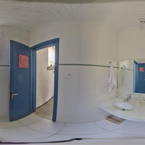 a bathroom with a sink and a blue door at Brasileranza Hostel in Niterói
