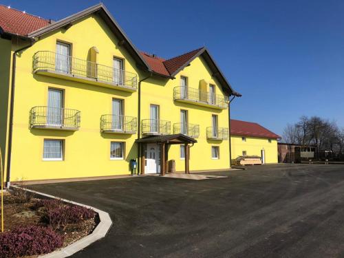 a yellow building with a parking lot in front of it at Bed and Breakfast Albatros in Perušić