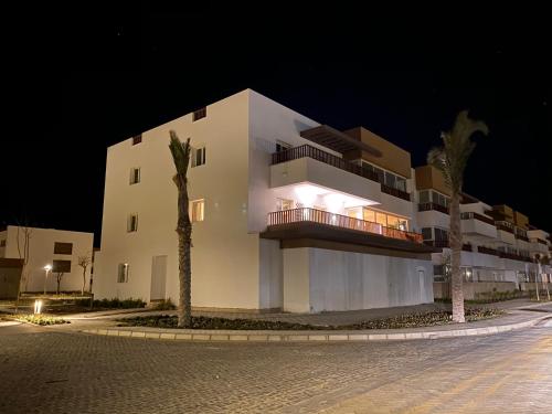 a large white building at night with two palm trees at Almaza bay Beach Town Chalet in Marsa Matruh