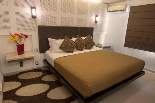 a bedroom with a large bed and a vase of flowers at Hotel Rio Tequisquiapan in Tequisquiapan