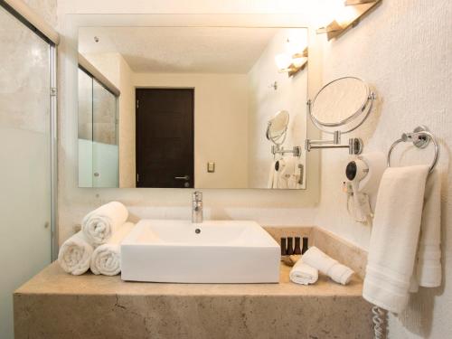 a bathroom with a sink and a mirror and towels at Hotel Rio Tequisquiapan in Tequisquiapan