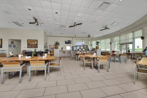 a restaurant with wooden tables and chairs and windows at Peninsula Island Resort & Spa - Beachfront Property at South Padre Island in South Padre Island
