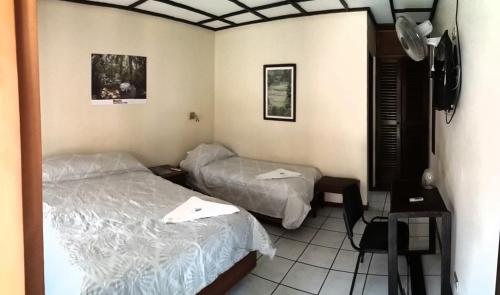 a hotel room with two beds and a tv at Hotel Wagelia Turrialba in Turrialba