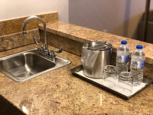 Radisson Lackawanna Station Hotel Scranton في سكرانتون: طاولة مطبخ مع حوض وزجاجتين من الماء