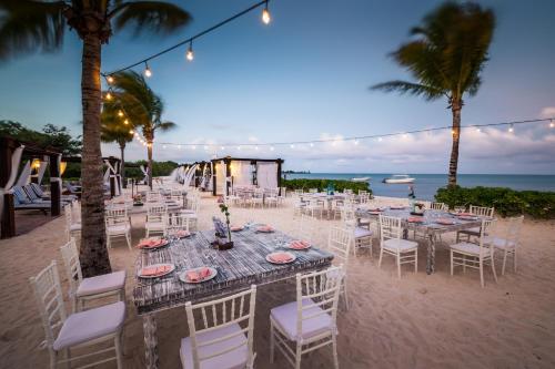 a table and chairs on a beach with the ocean at BlueBay Grand Esmeralda-All Inclusive in Playa del Carmen