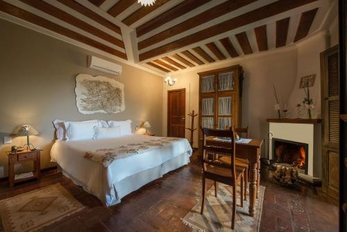 a bedroom with a bed and a desk and a fireplace at Quinta dos Pinhais Pouso e Charme in Santo Antônio do Pinhal