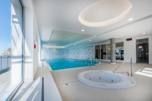 a large swimming pool in a building with a tub at CITYSTAY Waterlane Island Apartment in Gdańsk