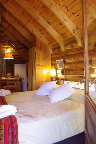 a large bed in a room with wooden ceilings at Cabañas Am Hang in La Cumbrecita