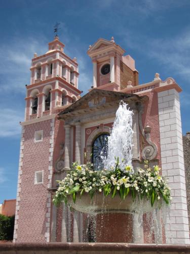 a building with a fountain in front of a clock tower at Hotel Rio Tequisquiapan in Tequisquiapan