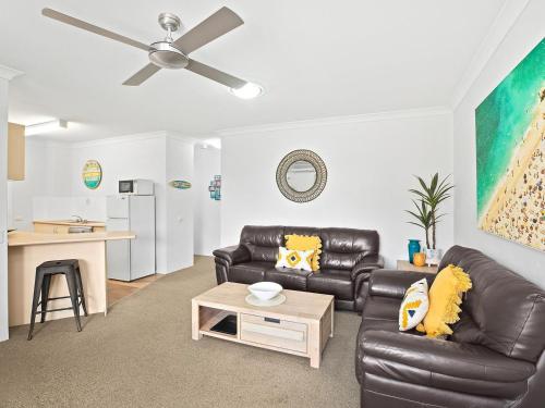 a living room with two leather couches and a table at Sandcastles Holiday Apartments in Coffs Harbour