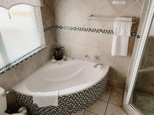 a bathroom with a bath tub and a shower at Sunbird View in Langebaan
