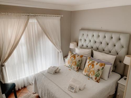 a bedroom with a white bed with pillows and a window at Sunbird View in Langebaan