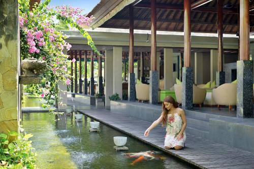 a woman standing on a dock looking at a kite in the water at Legian Beach Hotel in Legian