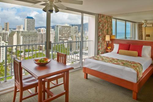 a bedroom with a bed and a desk and a large window at Pacific Monarch Hotel in Honolulu