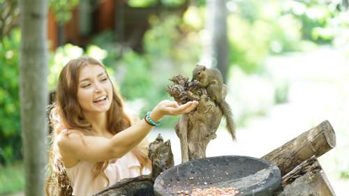 a young woman holding a squirrel on a statue at Legian Beach Hotel in Legian