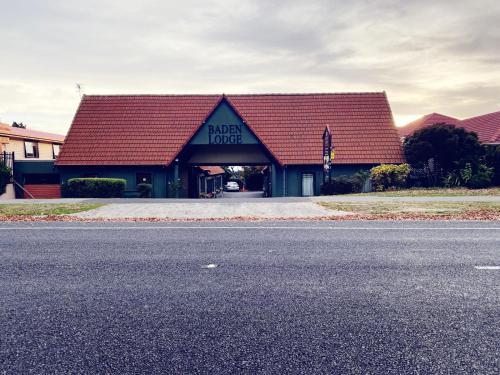 a building with a red roof on the side of a road at Baden Lodge in Rotorua