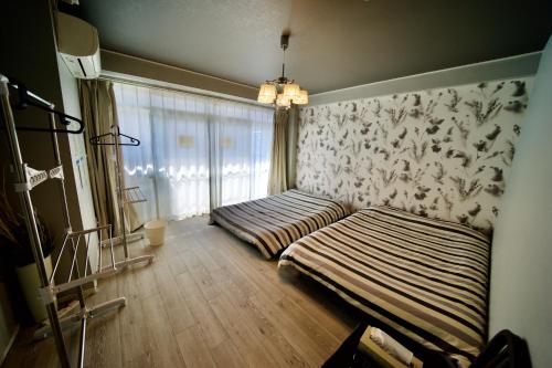 1 Schlafzimmer mit 2 Betten und einem Fenster in der Unterkunft Guest House Re-worth Joshin1 2F in Nagoya