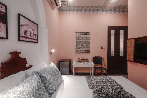 a bedroom with a bed and a table and a desk at The Mansion Hoi An by Minova in Hoi An