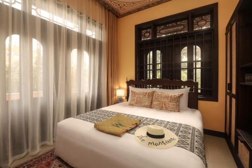 a bedroom with a bed with a hat on it at The Mansion Hoi An by Minova in Hoi An