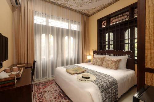 a bedroom with a large bed and a window at The Mansion Hoi An by Minova in Hoi An