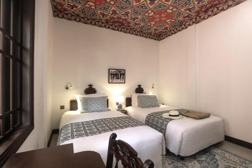 a room with two beds and a table and a table sidx sidx sidx at The Mansion Hoi An by Minova in Hoi An
