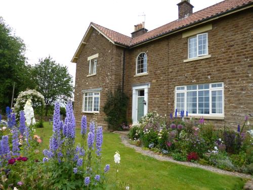 Hall Farm Bed & Breakfast في Terrington: منزل أمامه حديقة من الزهور