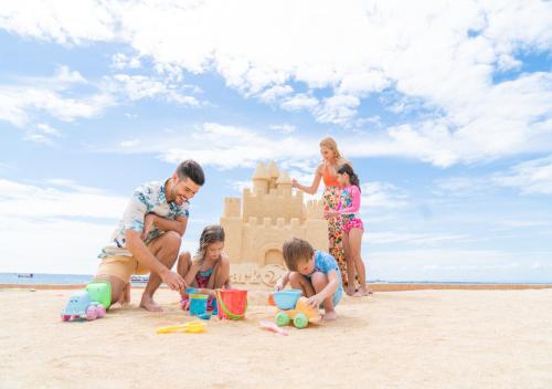 a family playing with a sand castle on the beach at Jpark Island Resort & Waterpark Cebu in Mactan