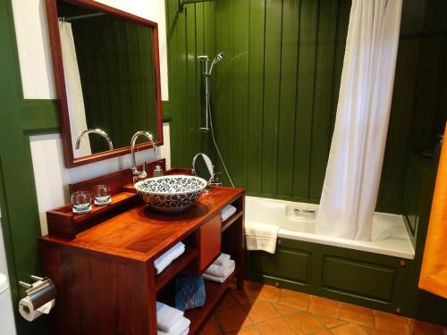 a bathroom with green walls and a sink and a tub at Villa Maydou Boutique Hotel in Luang Prabang