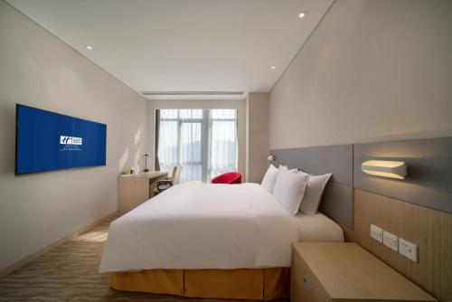 a hotel room with a large bed and a tv at Holiday Inn Express Qingdao Innovation Park by IHG in Qingdao