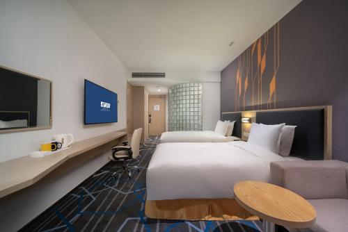a hotel room with two beds and a tv at Holiday Inn Express Qingdao Innovation Park by IHG in Qingdao
