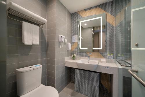 a bathroom with a toilet and a sink and a mirror at Holiday Inn Express Qingdao Innovation Park by IHG in Qingdao