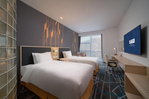 a hotel room with two beds and a tv at Holiday Inn Express Qingdao Innovation Park by IHG in Qingdao