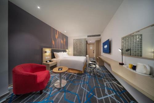 a hotel room with a bed and a red chair at Holiday Inn Express Qingdao Innovation Park by IHG in Qingdao