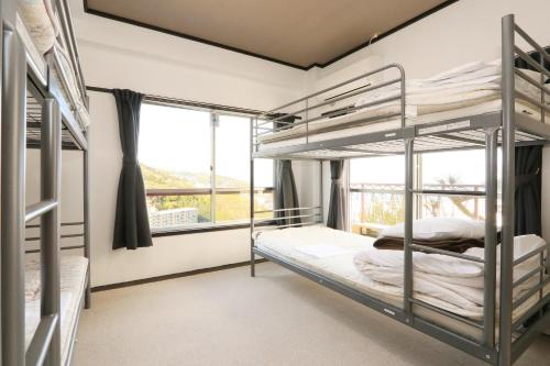 伊東的住宿－荘荘旅館，一间卧室设有双层床和窗户。