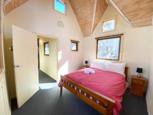 a bedroom with a large bed with a red blanket at Snowdragon in Dinner Plain