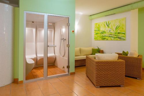 ein Bad mit einer Dusche und einem Sofa in einem Zimmer in der Unterkunft ACANTUS Hotel in Weisendorf