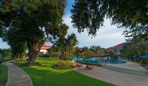 a park with a swimming pool and trees and buildings at Dheva Mantra Resort in Kanchanaburi City