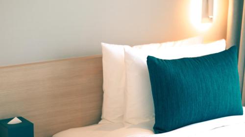 a close up of a bed with a blue pillow at Connect Busan Hotel & Residence in Busan
