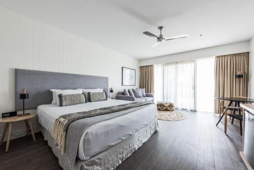 a white bedroom with a large bed and a ceiling fan at Waves Byron Bay in Byron Bay