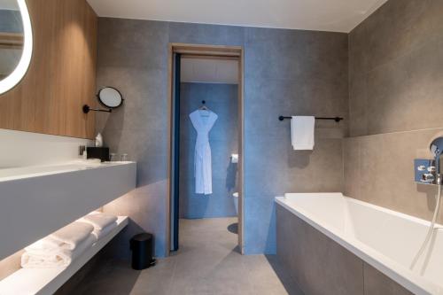 ein Badezimmer mit einer weißen Badewanne und einem Kleid auf einer Puppe in der Unterkunft Best Western Premier Hotel de la Paix in Reims