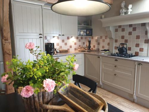 een keuken met een tafel met roze bloemen erop bij Het Stalhuys in Reeuwijk