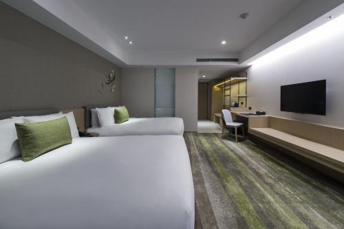 a hotel room with two beds and a television at Golden Tulip FAB Hotel New Taipei in Tamsui