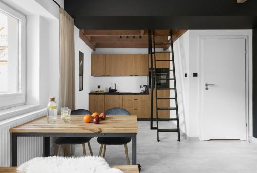 a kitchen with a wooden table and chairs and a ladder at Aparthotel Narciarska 2 in Korbielów