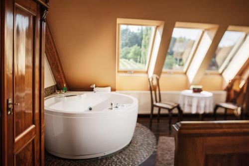 ein Bad mit einer großen weißen Badewanne in einem Zimmer in der Unterkunft Weingartenhotel Harkamp Südsteiermark in Sankt Nikolai im Sausal