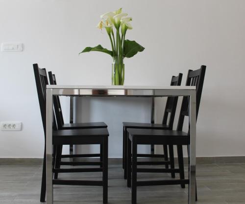 a glass table with chairs and a vase with flowers at Apartments Tom in Mimice